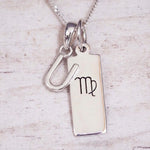 sterling silver initial v virgo zodiac star sign pendant necklace against a light wooden background