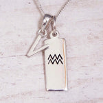 Sterling Silver V Initial and Aquarius Necklace on a fine silver chain against a light wooden background