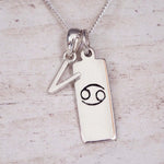 Sterling Silver V Initial Cancer Zodiac Star Sign Necklace on a fine silver chain against a light wooden background