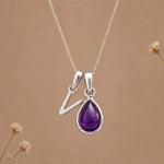 sterling silver initial v february birthstone natural amethyst pendant necklace against a dark warm beige background