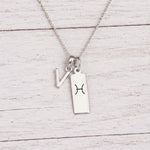 sterling silver V initial Pisces Necklace on a fine silver chain against a light wooden background