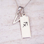 sterling silver initial v sagittarius zodiac star sign pendant necklace against a light wooden background