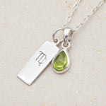 Sterling Silver necklace with a teardrop august birthstone peridot pendant and virgo zodiac pendant on a light background.
