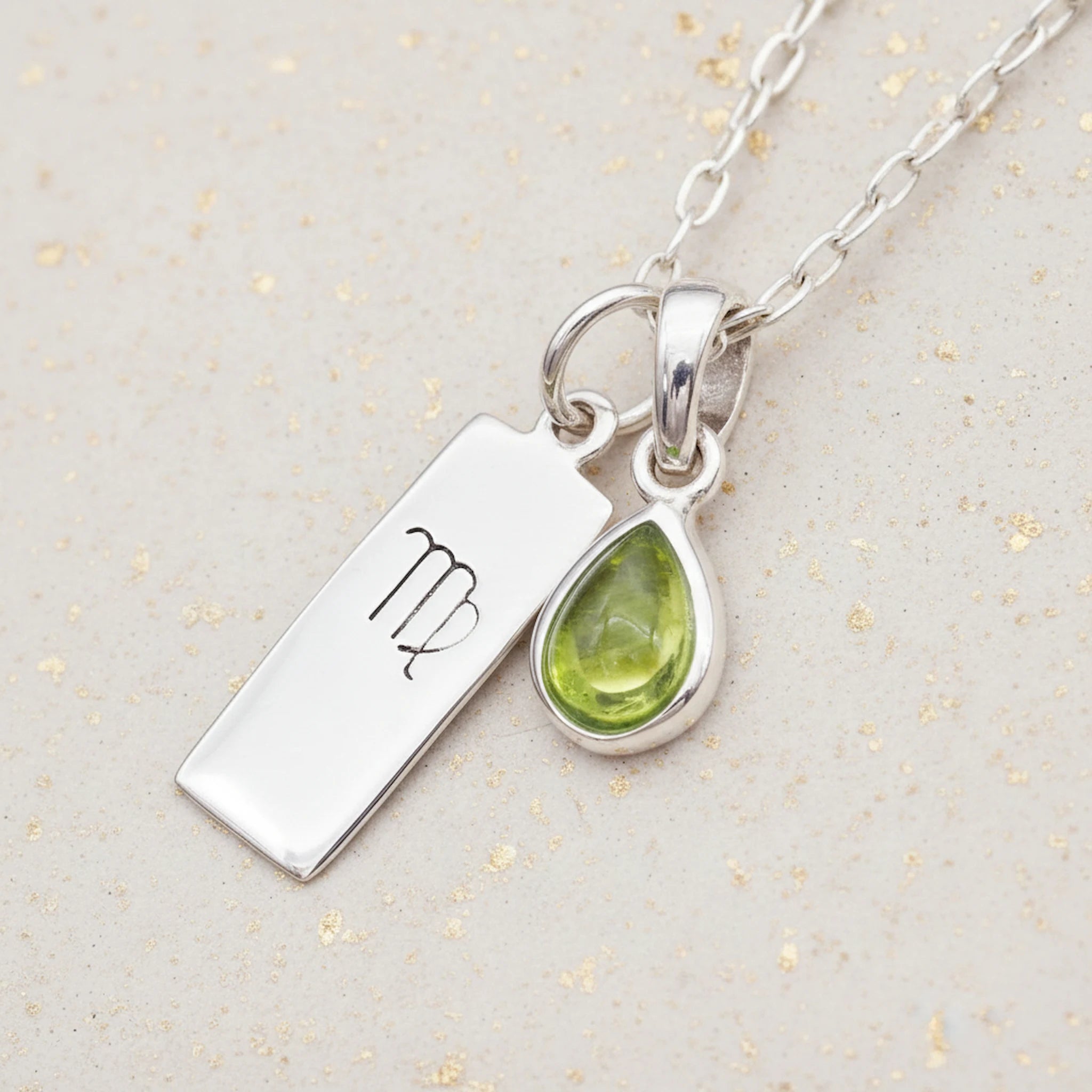 Sterling Silver necklace with a teardrop august birthstone peridot pendant and virgo zodiac pendant on a light background.