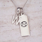 Sterling Silver W Initial Cancer Zodiac Star Sign Necklace on a fine silver chain against a light wooden background