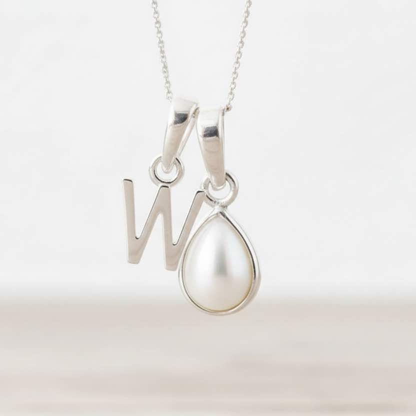 Silver necklace with a 'W' pendant and a teardrop-shaped pearl on a light background