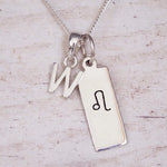 sterling silver initial w leo zodiac star sign pendant necklace against a light wooden background