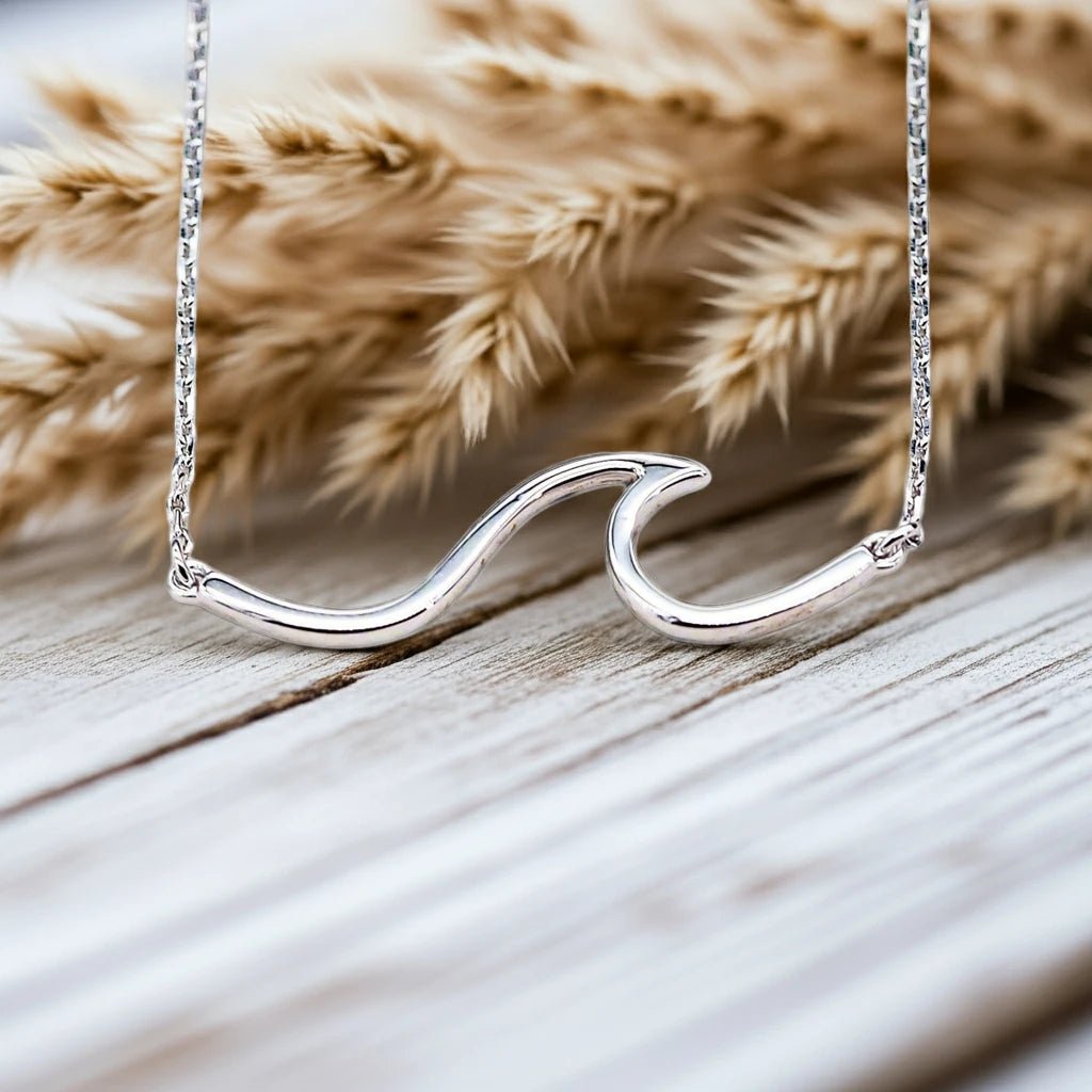 sterling Silver wave-shaped necklace on a wooden surface with dried pampas grass - indie and harper australian jewellery