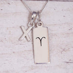 Sterling Silver X Initial pendant and Aries necklace on a fine silver chain on a light wooden background