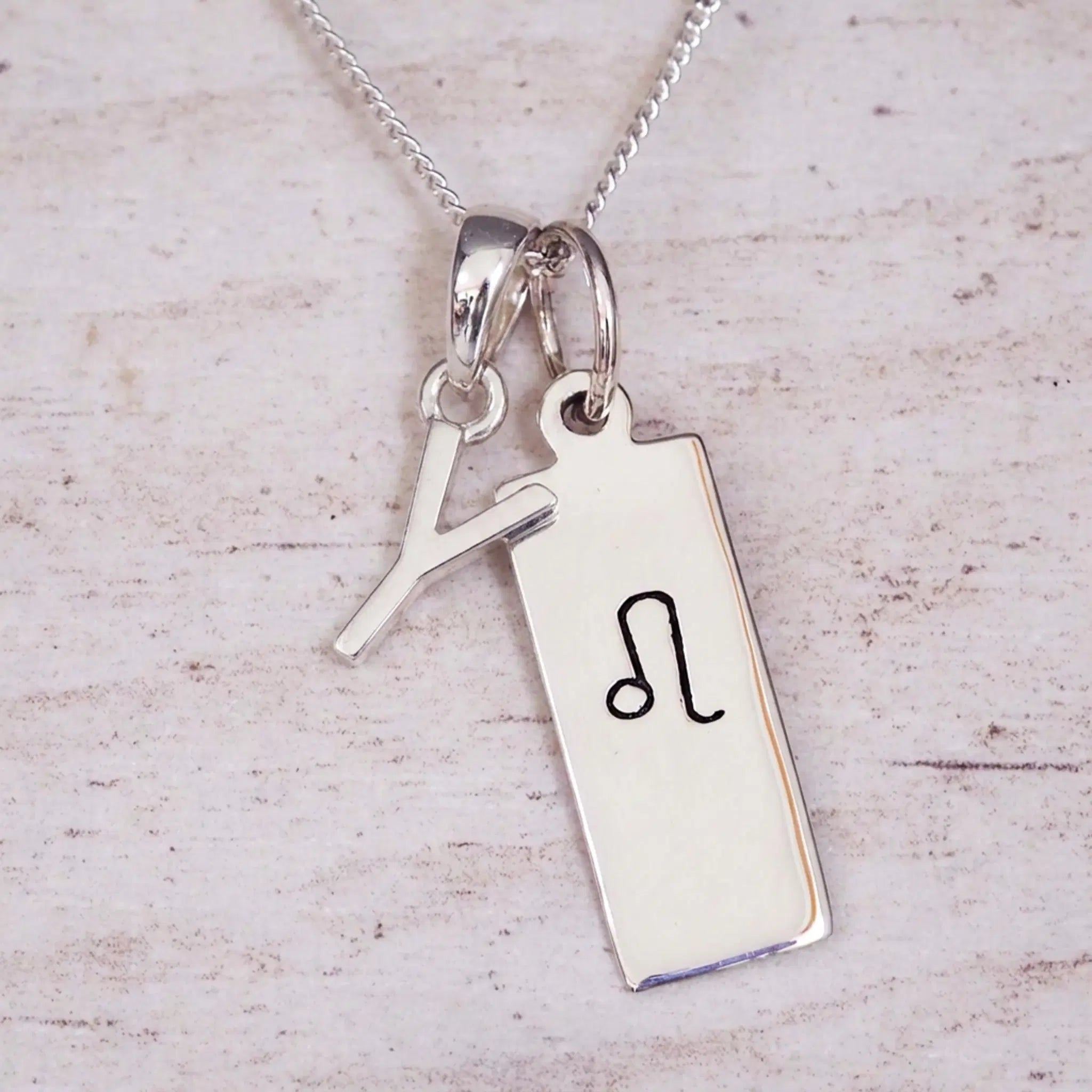 sterling silver initial y leo zodiac star sign pendant necklace against a light wooden background