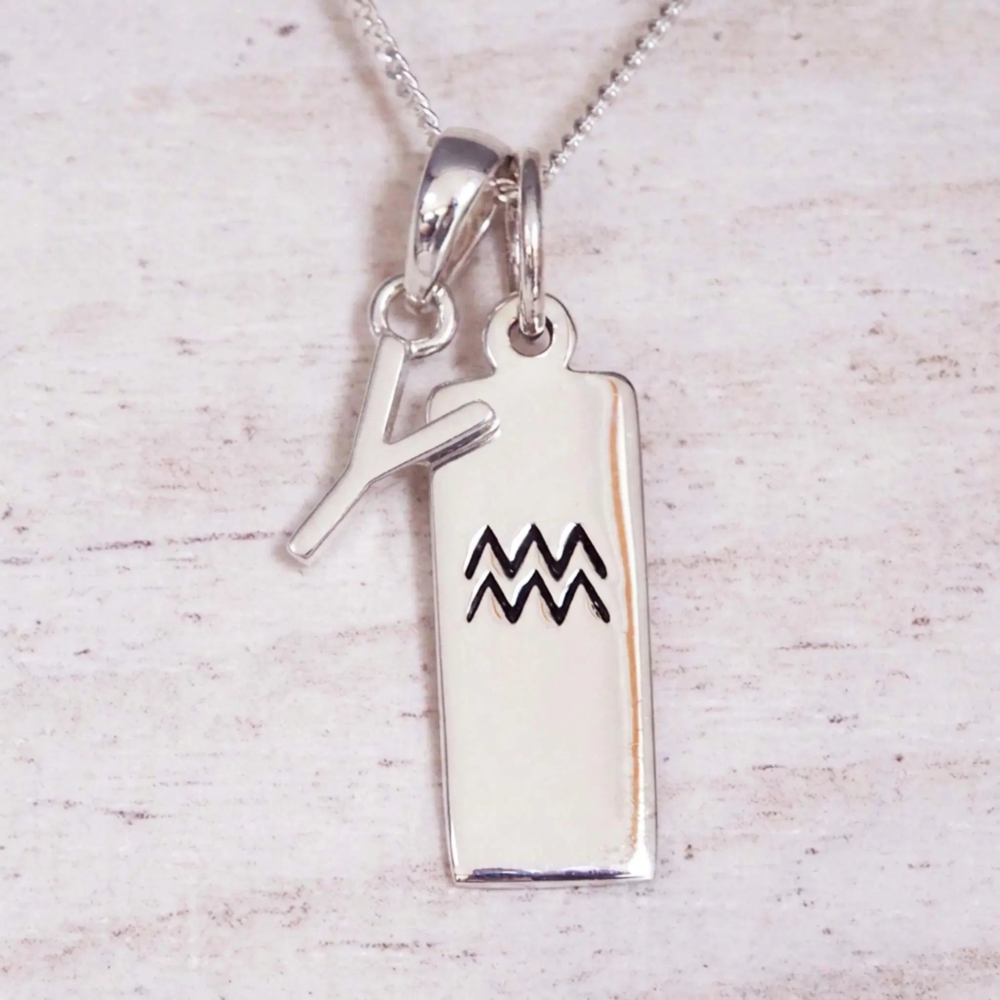 Sterling Silver Y Initial and Aquarius Necklace on a fine silver chain against a light wooden background