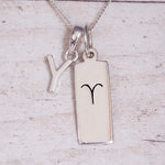 Sterling Silver Y Initial pendant and Aries necklace on a fine silver chain on a light wooden background