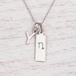 sterling silver initial Y pendant and capricorn necklace on a fine silver chain against a light wooden background