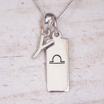sterling silver initial y libra zodiac star sign pendant necklace against a light wooden background