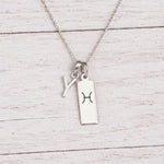 sterling silver Y initial Pisces Necklace on a fine silver chain against a light wooden background
