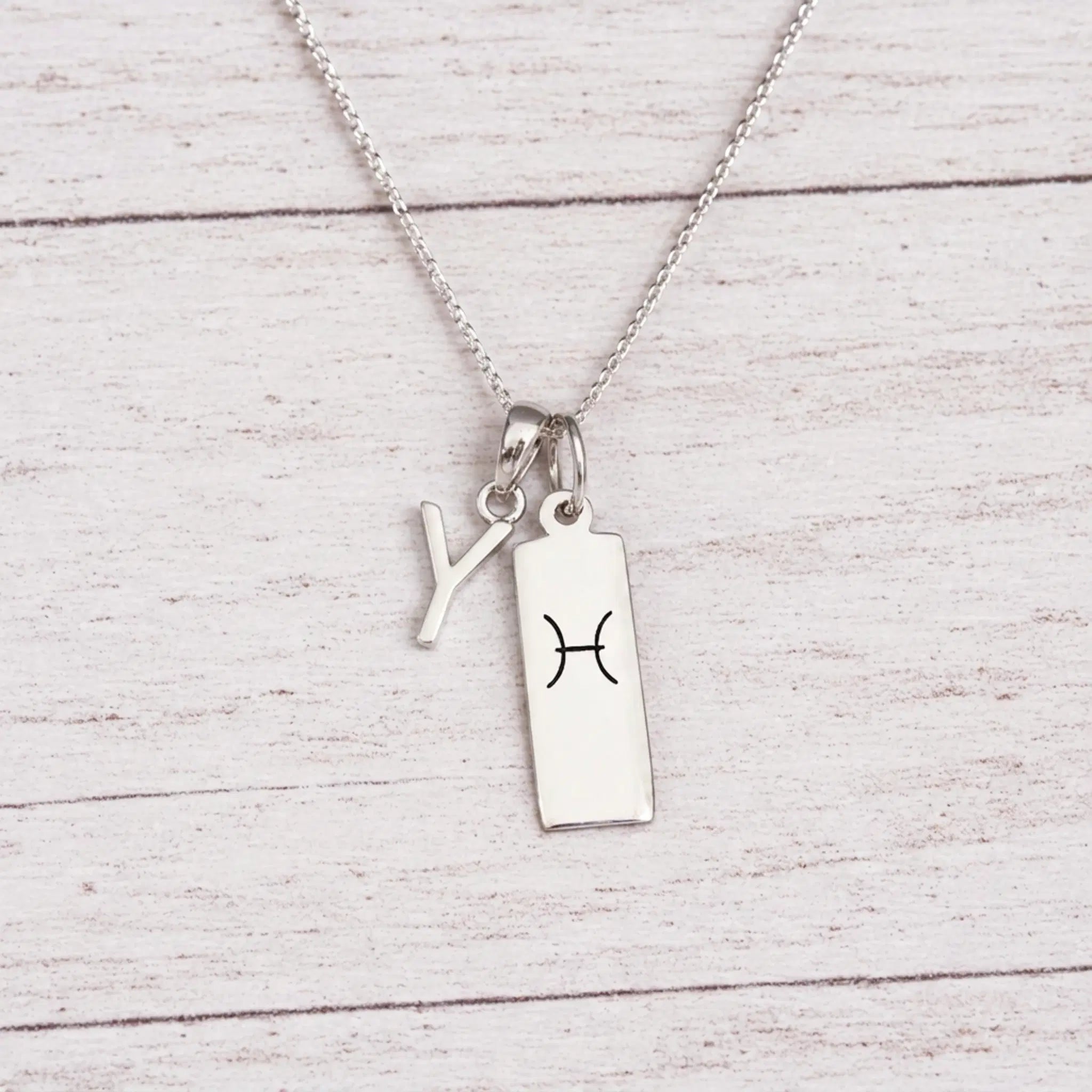 sterling silver Y initial Pisces Necklace on a fine silver chain against a light wooden background