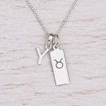 Sterling silver Y initial Pendant and Taurus Necklace on a fine silver chain on a light wooden background