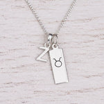 Sterling silver Z initial Pendant and Taurus Necklace on a fine silver chain on a light wooden background