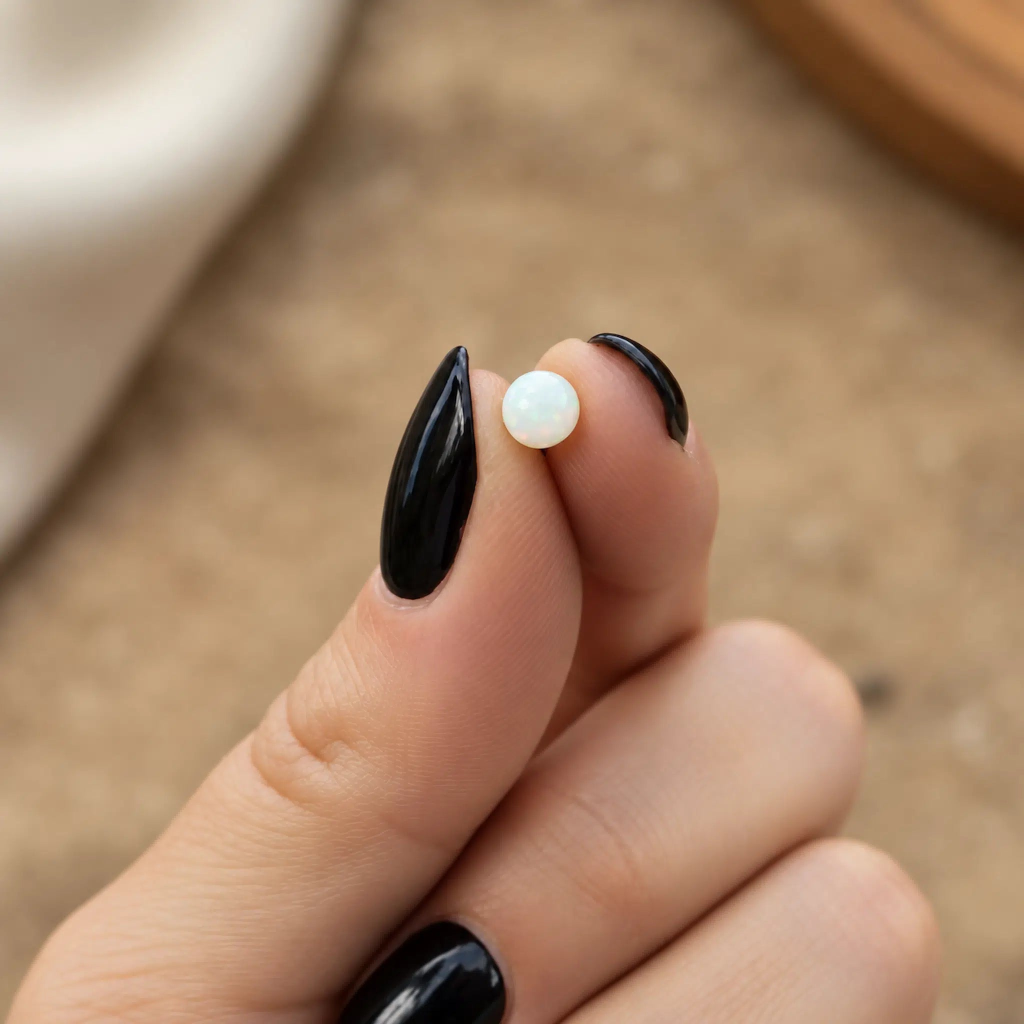 waterproof opal ball back stud earring being held