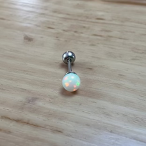 Belly button ring with a glowing gemstone on a wooden surface