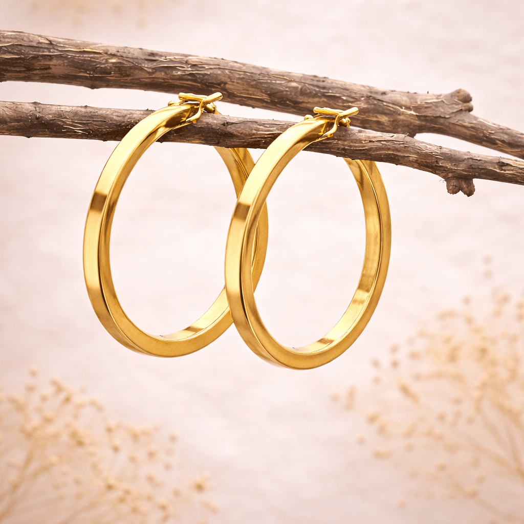Gold hoop earrings hanging on a branch with a soft background