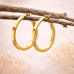 Gold hoop earrings hanging on a branch with a soft background
