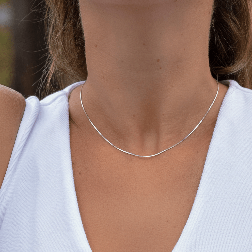 Silver necklace worn by a person with a blurred background