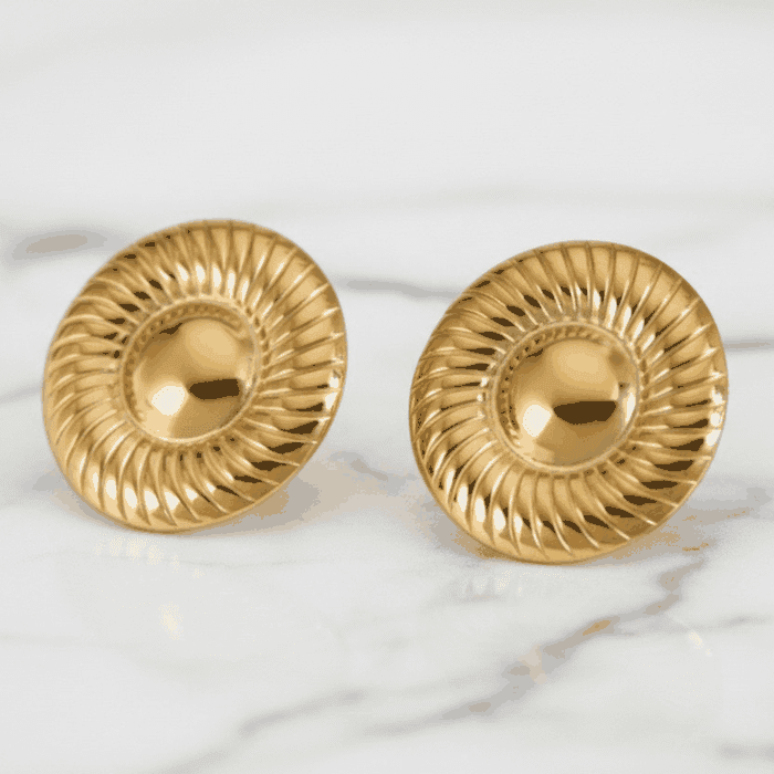 Pair of gold earrings on a marble surface