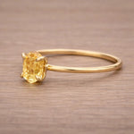 Gold ring with a yellow gemstone on a wooden surface