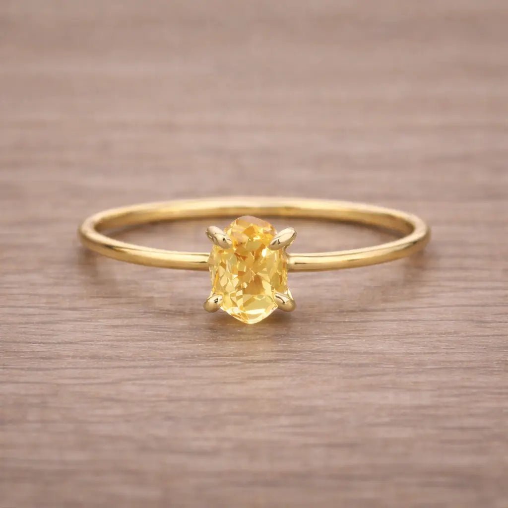 Gold ring with a yellow gemstone on a wooden surface