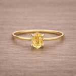 Gold ring with a yellow gemstone on a wooden surface