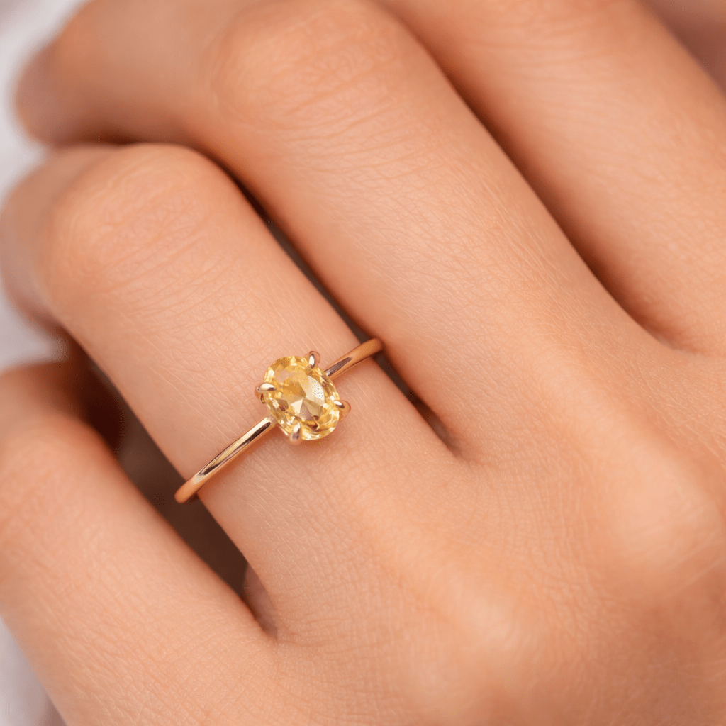 Gold ring with a yellow gemstone on a person's finger