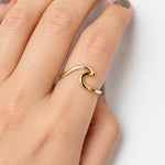 A close-up of a hand wearing a 9k solid gold wave ring with a curved, wave-like design on the ring finger.