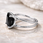 Silver ring with a black gemstone on a light background