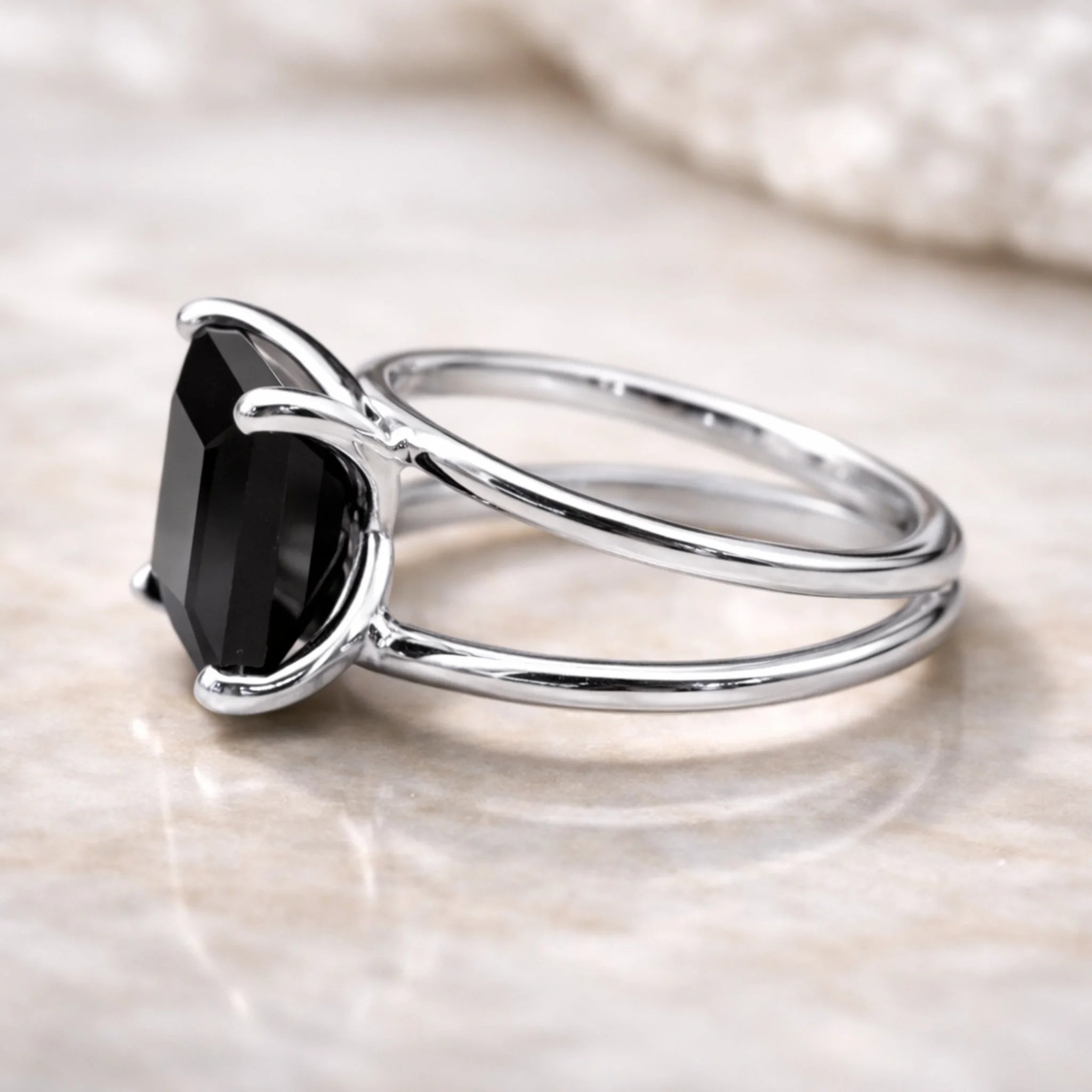 Silver ring with a black gemstone on a light background
