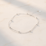 sterling silver anklet with double chain and silver ball beads on a soft white stone surface