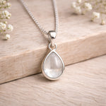Sterling Silver necklace with a teardrop-shaped natural herkimer quartz cabochon pendant on a wooden surface