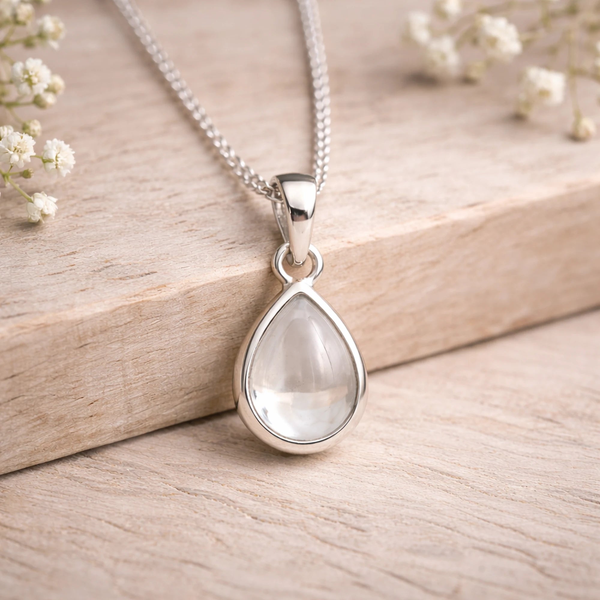 Sterling Silver necklace with a teardrop-shaped natural herkimer quartz cabochon pendant on a wooden surface