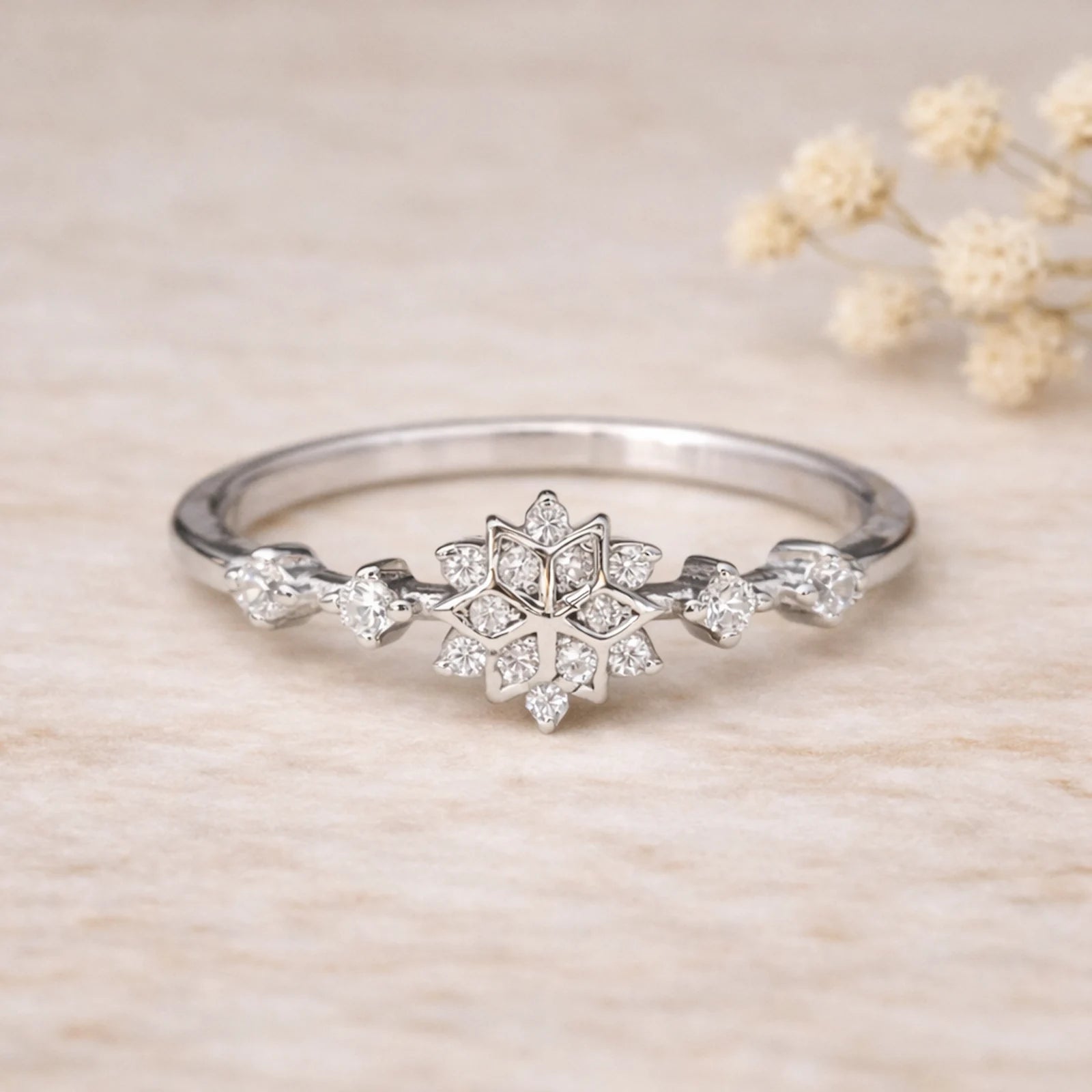 sterling Silver ring with snowflake celestial design with clear coloured cubic zirconia gemstones on a beige background