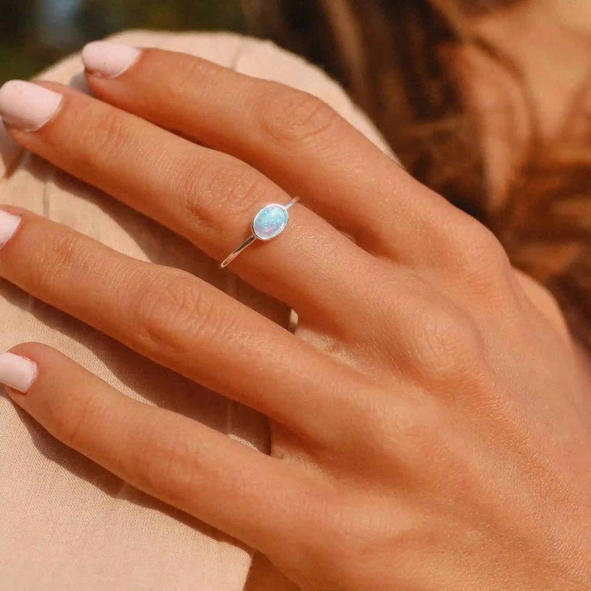 woman wearing a sterling silver dainty blue opal ring - lab-grown opal jewellery by womens jewelry brand indie and harper
