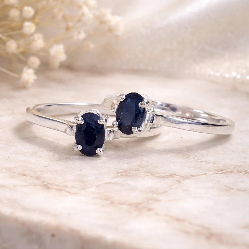 Sterling Silver Oval Claw Set faceted natural sapphire gemstone rings on a light stone surface