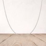 Silver chain necklace on a wooden surface with a light background