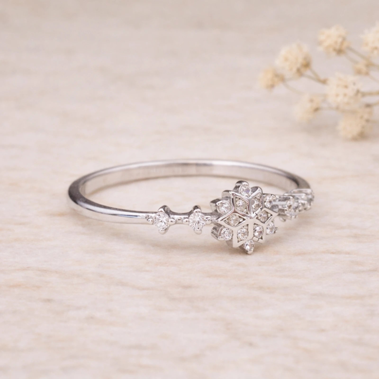 Sterling Silver ring with snowflake celestial cubic zirconia gemstone design on a beige background