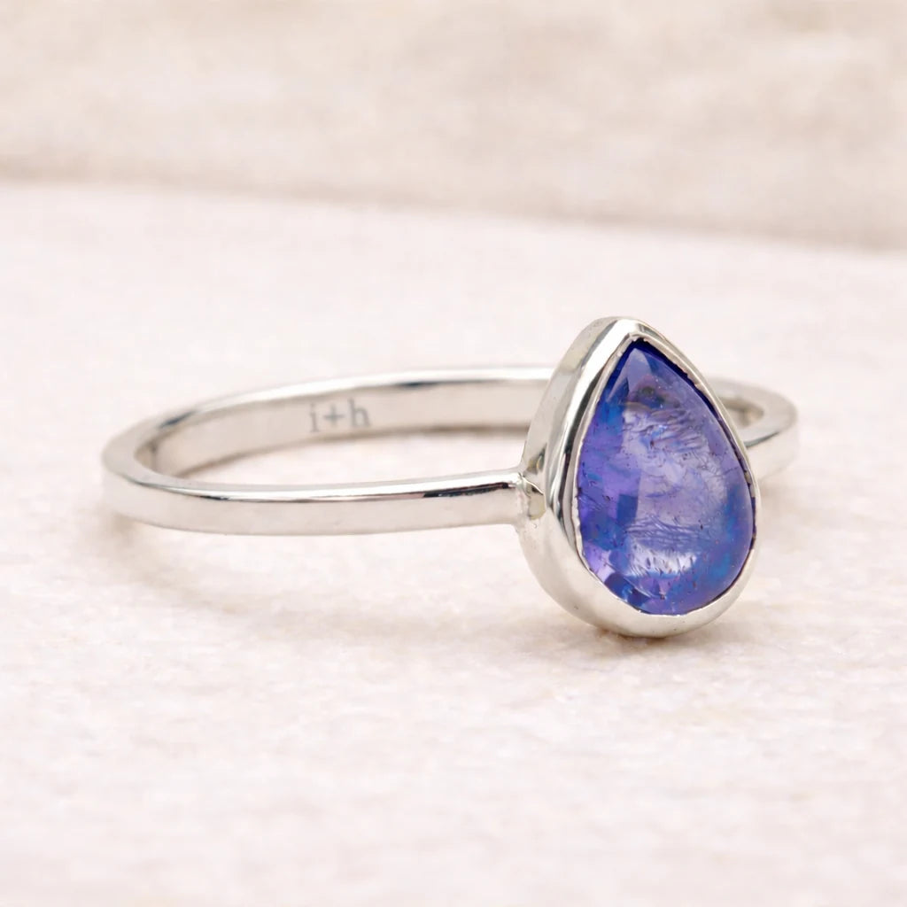 Silver ring with a teardrop-shaped natural tanzanite gemstone on a light background
