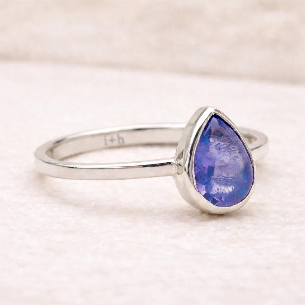 Silver ring with a teardrop-shaped natural tanzanite gemstone on a light background