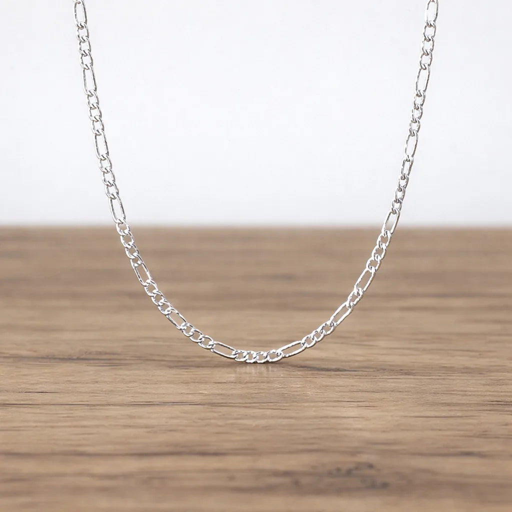 Silver chain necklace on a wooden surface with a white background