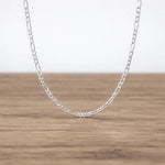 Silver chain necklace on a wooden surface with a white background