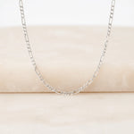 Silver chain necklace on a beige surface