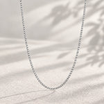 24 inch sterling silver flat curb chain, 1.5 mm, hanging against a soft neutral background