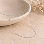 24 inch sterling silver 1.5 mm flat curb chain draped over a ceramic bowl